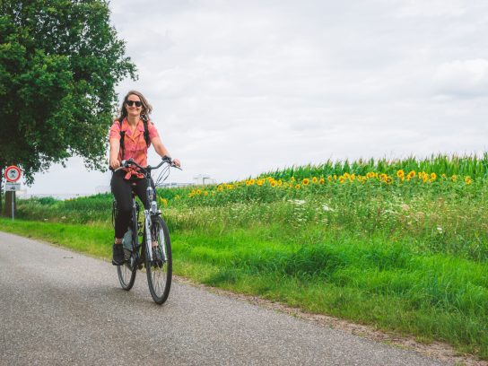 Persoon op een fiets die een fietsroute aan het afleggen is door de natuur, wat goed is voor je mentale gezondheid.