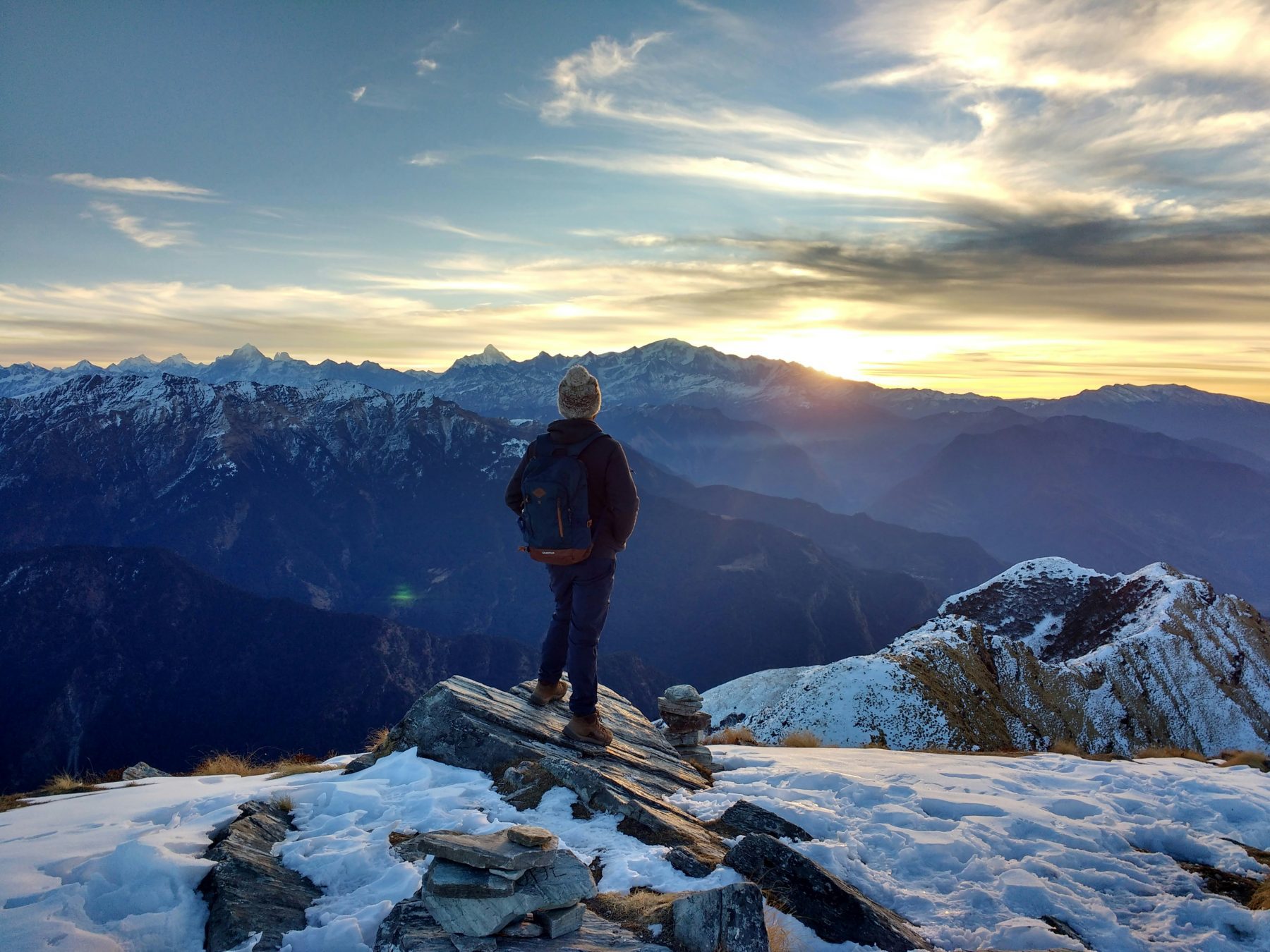 Een persoon die op de top van een berg in de Himalaya staat met uitzicht op de zonsopgang.